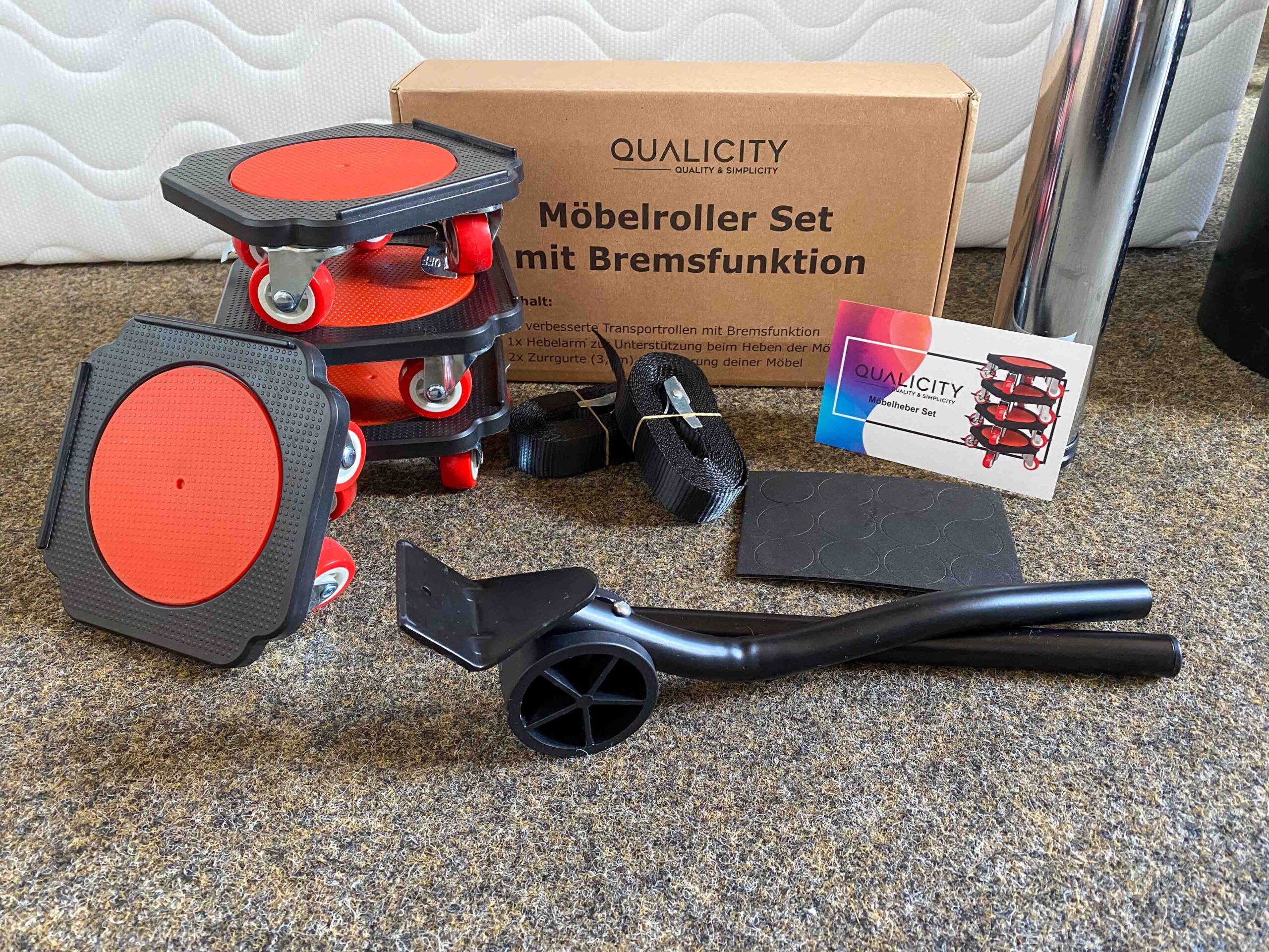Verpackungskarton im Hintergrund mit Möbelrollern, Karte, Hebelarm, Spanngurte und Anti-Rutsch Pads.