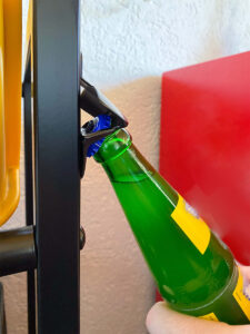 Flaschenöffner des Getränkekistenregals beim Öffnen einer grünen Glasflasche.