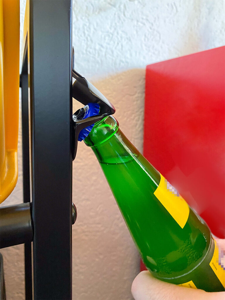 Flaschenöffner des Getränkekistenregals beim Öffnen einer grünen Glasflasche.