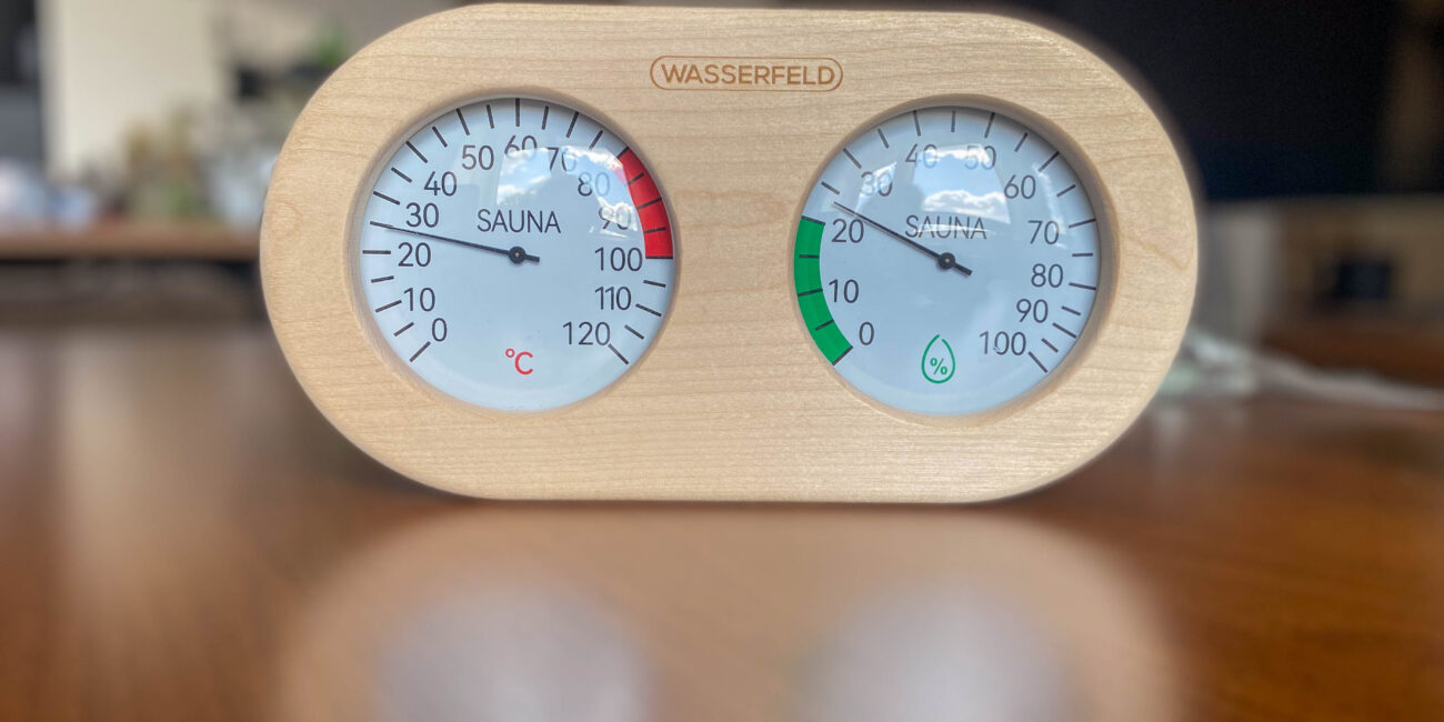 Saunathermometer und Hygrometer von Wasserfeld auf einem Tisch stehend.