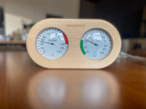 Saunathermometer und Hygrometer von Wasserfeld auf einem Tisch stehend.