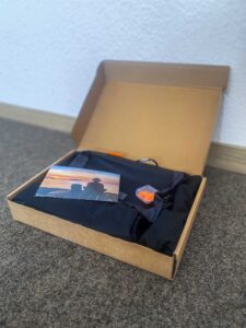 Hüttenschlafsack mit Beutel, Ohrenstöpseln Karte im Verpackungskarton seitlich von vorne.