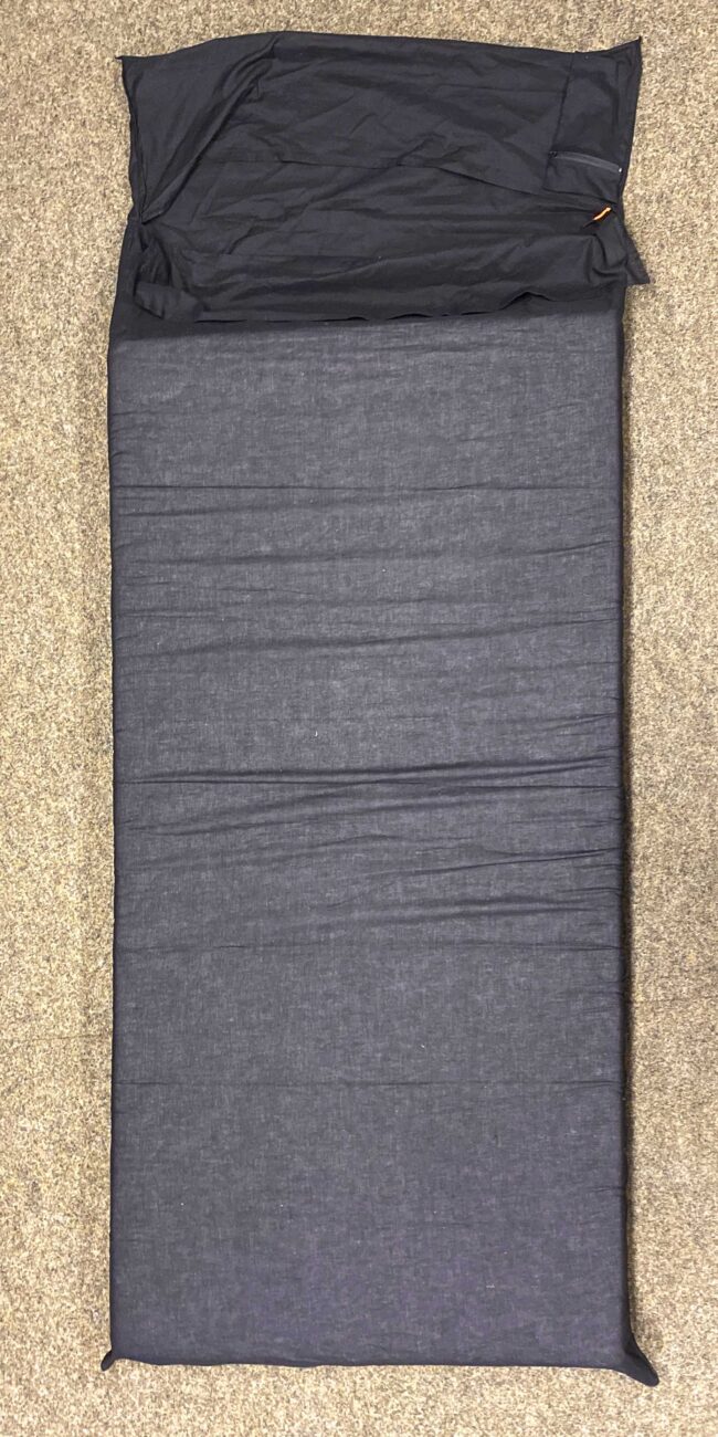 Schwarzer Hüttenschlafsack von Seeschwalbe auf Matratze auf dem Boden liegend bezogen.