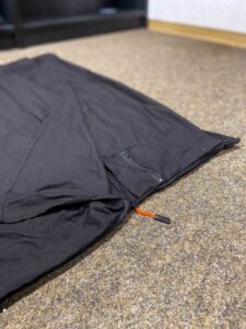 Hüttenschlafsack auf dem Boden liegend mit Seitentasche im Fokus.