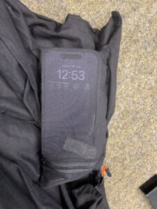 Wertsachen verstaut in der Wertsachentasche. Aufleuchtendes Smartphone schimmert durch den dünnen Baumwollstoff.