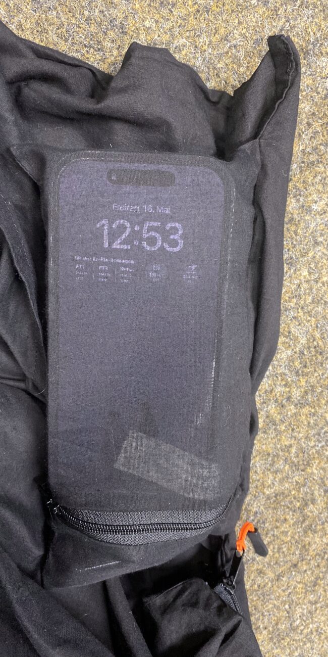 Wertsachen verstaut in der Wertsachentasche. Aufleuchtendes Smartphone schimmert durch den dünnen Baumwollstoff.