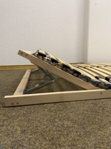 Halb aufgestellte Scharniere beim Lattenrost.