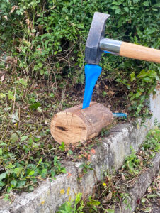 Holzspaltkeil im Spalt mit Hammer